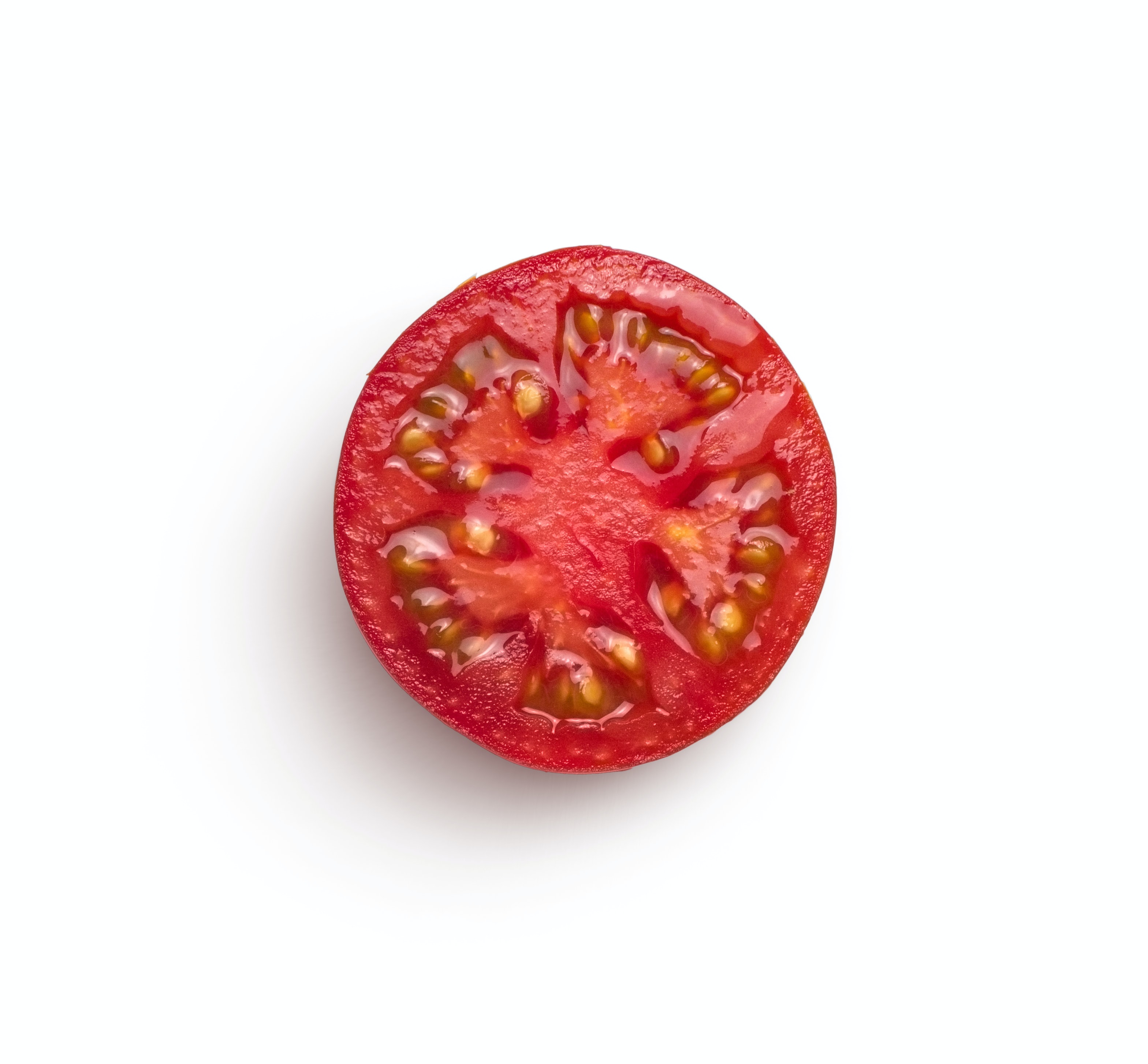 A very ripe tomato, cut in half, appears on a white background, seeds facing the camera.